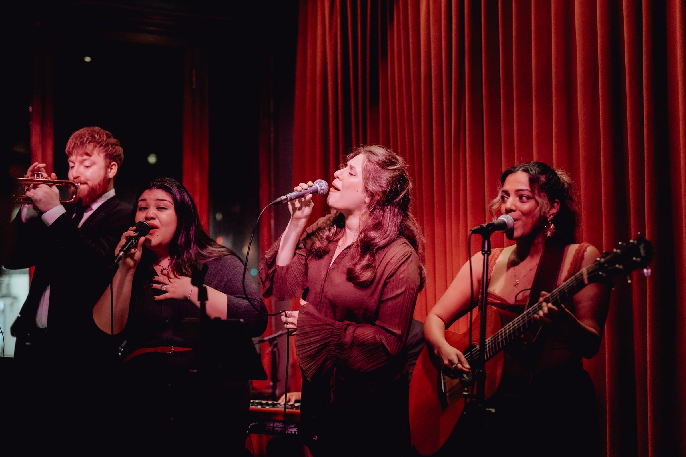 Singers performing on Cassette's stage in front of a red curtain