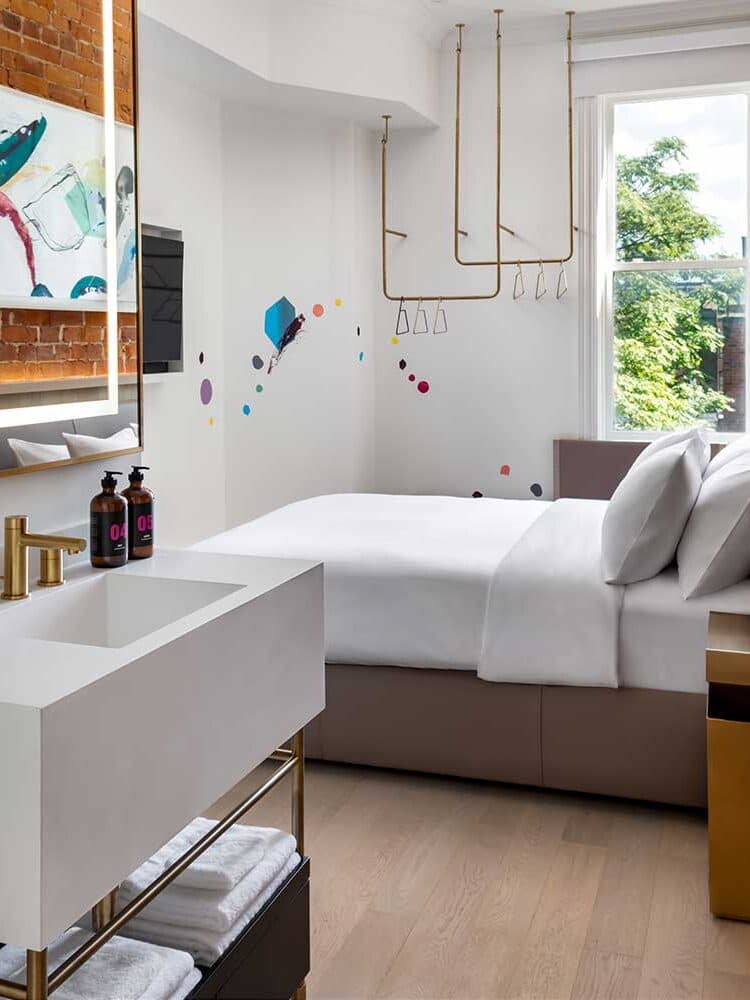 A Studio Queen guest room with a sink, hanging rack, and a window onto the street
